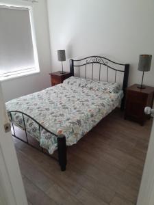 a bed in a bedroom with two night stands and two lamps at Red Kennel Budget Private Rooms - Trott Park in Happy Valley