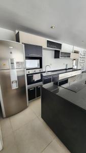 a kitchen with black and white counters and a refrigerator at De los Ñires Loft in Ushuaia +10 photos