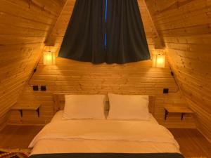 卡兹贝吉Kazbegi Harmony Cottages的木制客房的一张床位,配有两个枕头