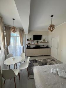 ein Wohnzimmer mit Tisch und Stühlen und einem Fernseher in der Unterkunft Mamaia Nord Lotus Residence 17 in Mamaia