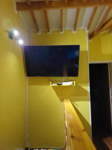 Zimmer mit einem TV an einer gelben Wand in der Unterkunft Cómoda casa familiar in Valdivia