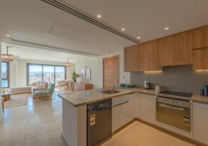 a kitchen with wooden cabinets and a living room at Ancient Hill 3BR Gouna Sea View & Priv Roof Pool in El Gouna