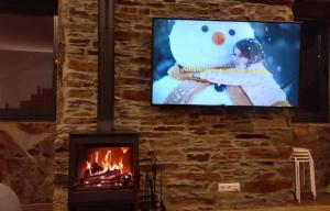 a fireplace with a tv and a snowman on the screen at Quinta da Azenha in Nespereira