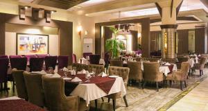 Un restaurante con mesas y sillas en una habitación. en Best Western City Center Gujranwala, en Gujrānwāla