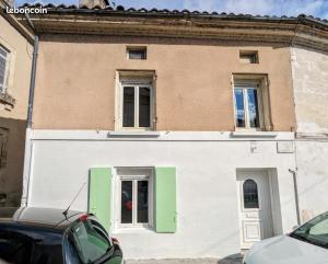 Maison Appartement plein Centre Saint Astier في Saint-Astier: مبنى أبيض وأخضر مع نافذتين