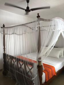a bedroom with a canopy bed with white curtains at La'Litha Villa in Bentota