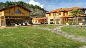 a large yellow building with a lawn in front of it at Casa las Vacas in Cervera de Pisuerga