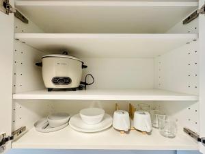 a kitchen with a toaster and dishes on shelves at Micasa at Green 2 Residences in Dasmariñas