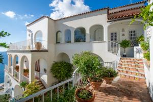 a white house with potted plants in front of the ocean at Estate4home - Regina Dar adults only in Positano