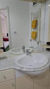 ein Badezimmer mit einem weißen Waschbecken und einem Spiegel in der Unterkunft Central City 2 Apartman in Debrecen