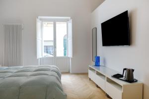 een witte slaapkamer met een bed en een tv aan de muur bij Coppola Suite in Lecce