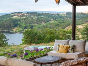 a porch with a couch and a view of a lake at TAMACA nature in Marco de Canaveses