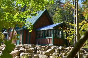 a cabin in the woods with rocks in front of it at Trekker, Treehouses cabins and lodge rooms in Lake George