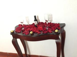 a table with two wine glasses and red roses at Posada Los Helechos in Villa de Leyva