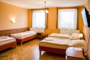 3 łóżka w pokoju z żółtymi ścianami w obiekcie Hotel U Jezera w mieście Velký Osek
