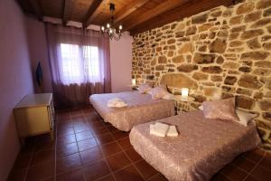 Zimmer mit 2 Betten und einer Steinmauer in der Unterkunft Casa rural San Felices in San Felices de Castillería