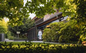 a woman standing in front of a building at YONA ex Le Parc Hôtel in Obernai