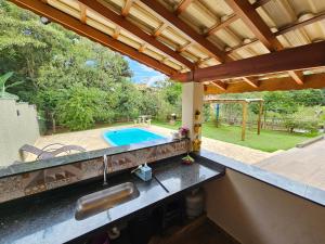 an outdoor kitchen with a sink and a swimming pool at Recanto Margarida in Socorro