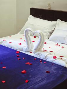 two swans shaped like hearts are laying on a bed at Moonlight Tourist Home in Erāttupetta