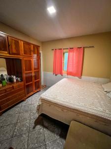 a bedroom with a bed and a window with red curtains at kasada Nanda in Pirenópolis +8 photos