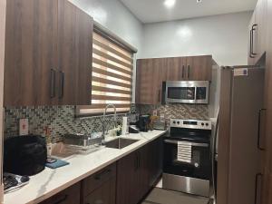 Una cocina con gabinetes de madera y electrodomésticos de acero inoxidable. en Syxx Old Church Road, en Kingston