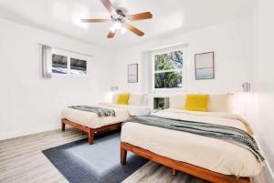 two beds in a white room with a ceiling fan at Gilmore Grove in Reseda in Los Angeles