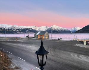 a street light next to a road with a house on the water at Sognefjord Gjesteheim in Vangsnes