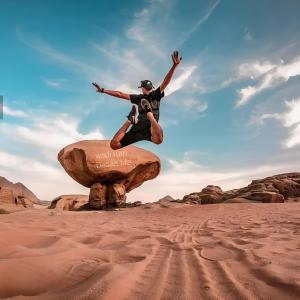 un hombre saltando de una roca en el desierto en Wadi Rum Desert Life, en Wadi Rum