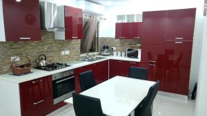 a kitchen with red cabinets and a table with chairs at Apartment Marsascala Seafront in Il-Kappara
