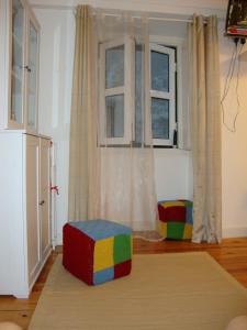uma sala de estar com um repousa-pés colorido em frente a uma janela em Regueira Apartment em Lisboa