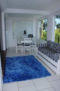 a living room with a table and a blue rug at Lindo Loft a beira Mar em Ilha Bela Acesso ao mar in Ilhabela