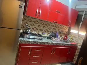 a red kitchen with a sink and red cabinets at Appartement a settat in Settat