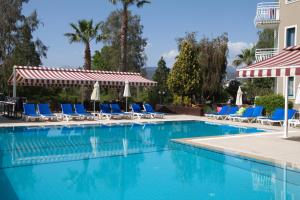 a swimming pool with blue chairs and umbrellas at Remer Hotel in Fethiye