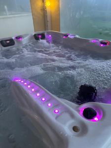 eine weiße Badewanne mit violetten Lichtern darin in der Unterkunft Les oiseaux du paradis in Saint-Antoine-de-Breuilh