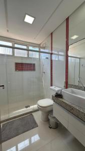 a bathroom with a toilet and a sink and a shower at PERFEITO!!! Apartamento de 3 quartos com ar-condicionado a 30 metros da Praia do Morro in Guarapari +12 photos
