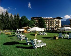 a group of lawn chairs and umbrellas in a park at Hotel Villa Argentina in Cortina dʼAmpezzo