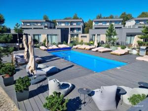 a hotel with a swimming pool with chairs and umbrellas at Cozy Palanga Apartment in Palanga