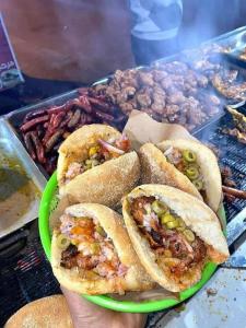 a person holding a plate of sandwiches and other food at too house in Al Mughayyir