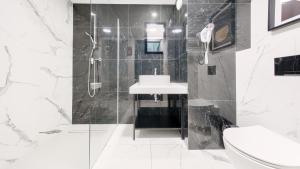 ein schwarz-weißes Badezimmer mit Waschbecken und Dusche in der Unterkunft Solny Resort Apartament in Kołobrzeg + 2 Fotos