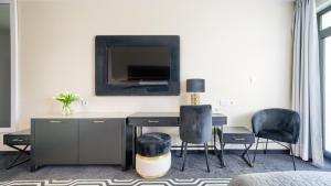 Zimmer mit einem Schreibtisch mit 2 Stühlen und einem TV in der Unterkunft Solny Resort Apartament in Kołobrzeg