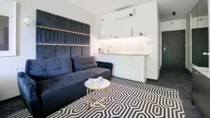 ein Wohnzimmer mit einem blauen Sofa und einem Tisch in der Unterkunft Solny Resort Apartament in Kołobrzeg