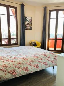 a bedroom with a bed and two windows and a chair at Appartement Marceau in Mers-les-Bains