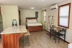 a room with a bed and a kitchen with a desk at Cottage 5 at Island Pearl Gold Standard Certified in Caye Caulker