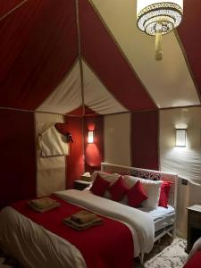 a bedroom with a red and white canopy bed at Merzouga Sahara Desert Camp in Merzouga
