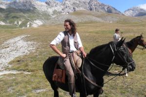 a man riding a horse in a field at L' Antico Casale in Le Marmore