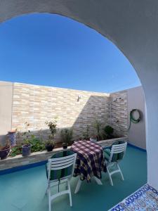 a patio with a table and chairs and a brick wall at Heimat am Meer in Sidi Ifni