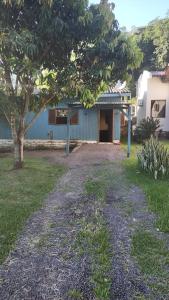 a house with a tree in front of a yard at Casa da Montanha in Rolante