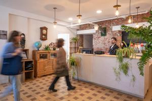 two people walking around a restaurant with a man sitting at a counter at Auberge de Jeunesse Les Balcons in Baie-Saint-Paul