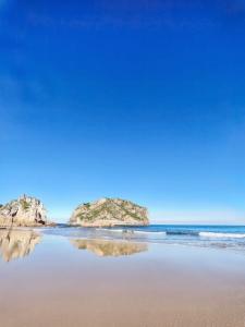 a beach with two large rocks in the water at Apartamento con jardín in La Franca +16 photos
