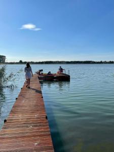 a woman walking on a dock next to a boat at Noclegi nad jeziorem Brdów Agroturystyka pod Wierzbą in Brdów